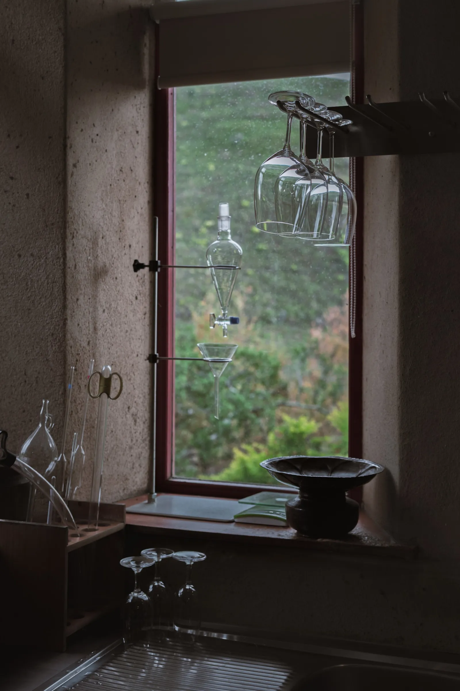 Two wine glasses on a windowsill overlooking vineyards